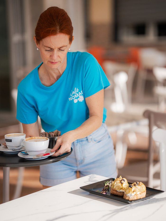 A member of the Café Nomad team carrying plates out to the terrace.